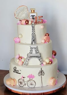 a three tiered cake decorated with the eiffel tower and paris themed decorations