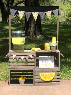 an outdoor lemonade stand on the side of a road in front of some trees