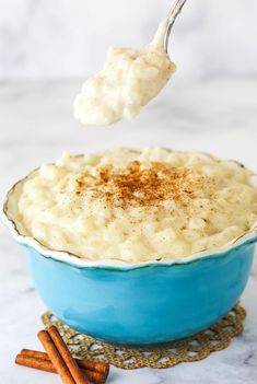 a spoon full of mashed potatoes with cinnamon sprinkles in a blue bowl