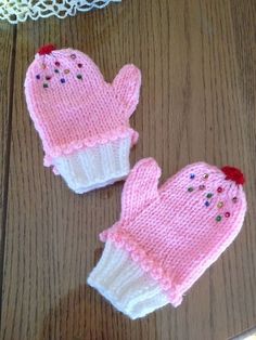 two knitted mittens sitting on top of a wooden table