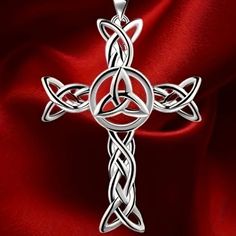 a silver celtic cross on a red satin background