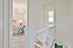 the stairs lead up to the second floor in this white house with wood floors and chandelier