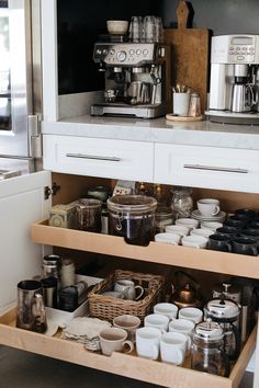 an open drawer in a kitchen filled with cups and saucers