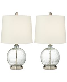 two clear glass table lamps with white shades on each lamp and one is turned off