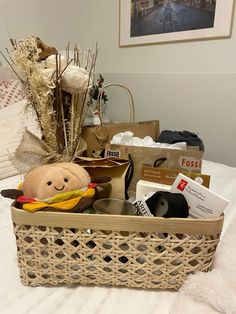 a basket filled with items sitting on top of a bed next to a pillow and pictures