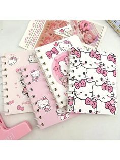 three notebooks with hello kitty designs on them and a pink clipboard next to it