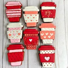 decorated cookies are arranged in rows on a white wooden surface, with hearts and shapes