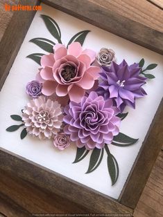 some paper flowers are in a wooden frame