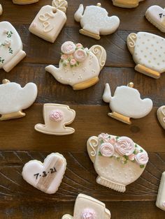 many decorated cookies are arranged on a wooden table with white and pink frosted decorations