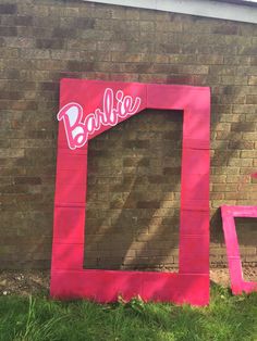 a pink frame with the word barbie painted on it in front of a brick wall