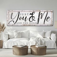 a white couch sitting next to a wooden sign that says, just you and me and the dogs