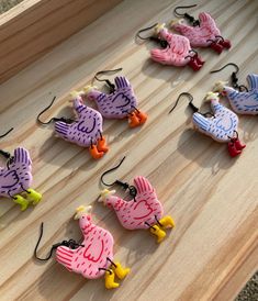 several different colored birds are hooked up to fishing hooks on a wooden board with string