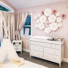 a baby's room decorated in pink and white with flowers hanging on the wall