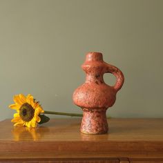 a vase sitting on top of a wooden table next to a sunflower