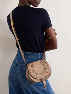 Chloé's 'Marcie' bag features so many of the label's hallmarks, from the saddle silhouette to the bohemian tassels. This mini version is made from textured-leather with just enough space inside for your wallet, cell phone and sunglasses, and has a tab-fastening front flap so you can access them easily. It’s finished with signature equestrian-style stitching and an embossed logo. Chloe Saddle Bag, Chloe Logo, Denim Flats, Chloe Shoulder Bag, Floral Dresses Short, Sport Swimwear, The Bohemian, Swimsuit Dress, Chloe Marcie