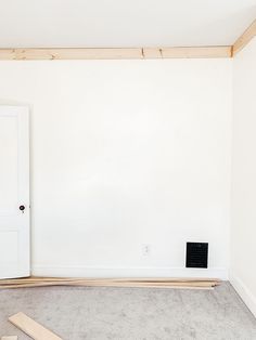 an empty room with white walls and wood framing on the floor next to a door