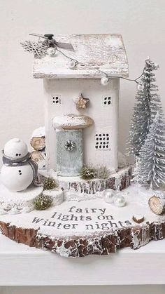 there is a small white house on top of a table with snowmen and trees