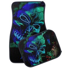 two blue and green skulls with glowing eyes on black floor mats, one has red glasses