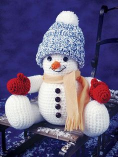 a knitted snowman sitting on a sled