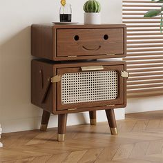 a wooden cabinet with two drawers and a smile face painted on the front, sitting next to a window