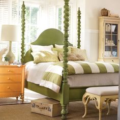 a green and white bedroom with four post bed, chest of drawers, nightstands and dresser