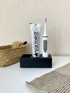 an electric toothbrush and tube of toothpaste sit on a table next to a basket