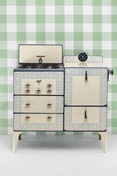 an old fashioned stove in front of a green and white checkerboard wallpaper