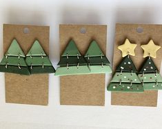 three christmas trees are hanging from brown paper with gold stars on them, and one is green