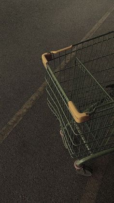 a green shopping cart sitting on the side of a road