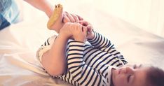 a little boy laying on top of a bed holding onto a piece of bread in his hand