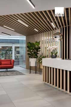 an office lobby with wood slats on the ceiling and red couch in the center