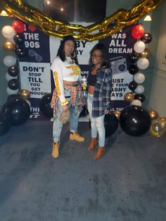 two women standing next to each other in front of balloons