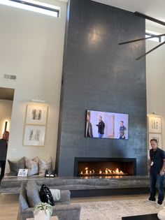 a man standing in front of a fireplace with two pictures on the wall above it