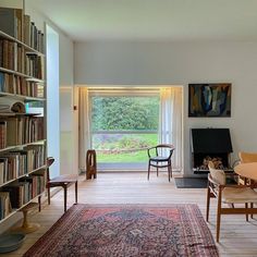 a living room filled with furniture and bookshelves next to a large open window