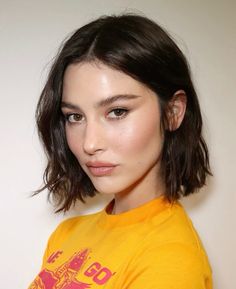 a close up of a person wearing a yellow t - shirt and posing for the camera