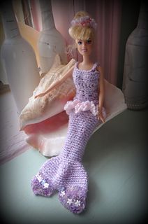 a doll is sitting on a table next to some vases and a mermaid tail