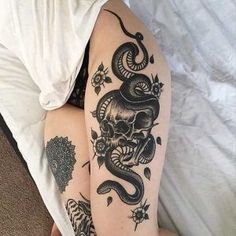 a woman with tattoos on her legs and arms is laying down next to a bed