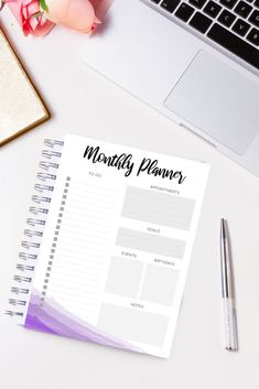 a notepad sitting on top of a white desk next to a laptop and flowers