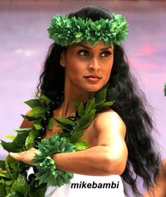 a woman with long black hair and green leaves on her head wearing a hula skirt