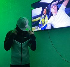 a man standing in front of a flat screen tv next to a wall mounted television