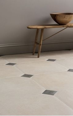 a wooden bowl sitting on top of a table next to a wall with tile flooring