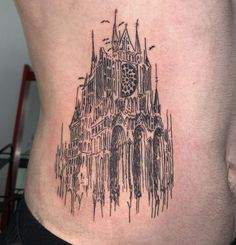 a tattoo on the side of a man's stomach with a cathedral in the background