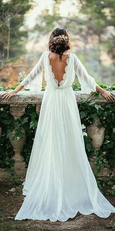 the back of a woman's wedding dress, with her arms on a wall