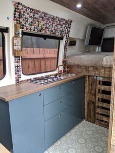 a kitchen area with blue cabinets and counter tops next to a bed in a trailer