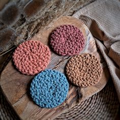 four crocheted coasters sitting on top of a wooden board