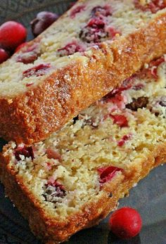 two loafs of fruit bread sitting on top of a black plate next to raspberries