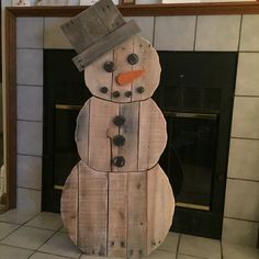 a snowman made out of wooden planks sitting in front of a fireplace