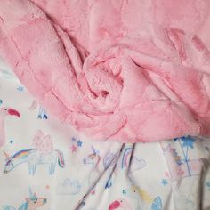 a pink blanket laying on top of a bed next to an unmade sheet and pillow