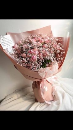 a bouquet of pink flowers is sitting on a white surface with a note attached to it