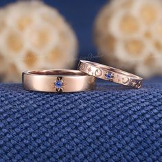 two gold wedding bands with blue sapphire stones on them sitting on top of a blue blanket